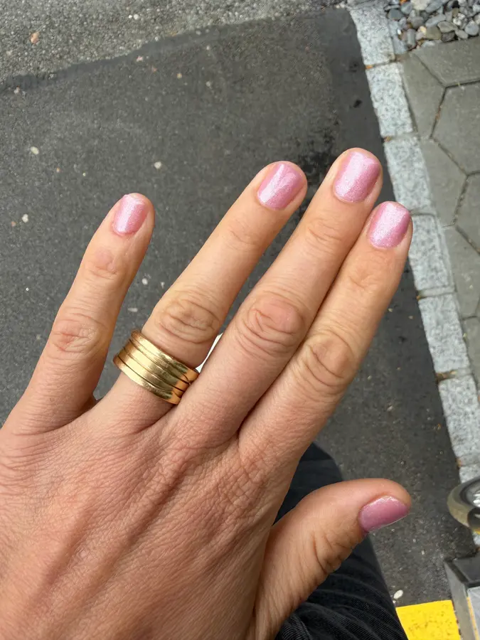Rosa Glitzer-Nägel mit breitem Goldring